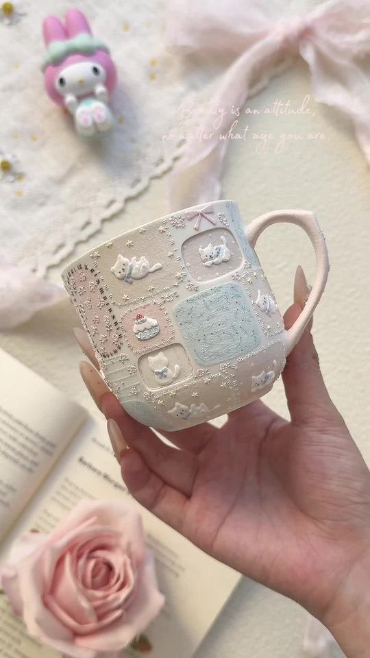 Handmade pastel ceramic mug with raised white cats and cake decorations